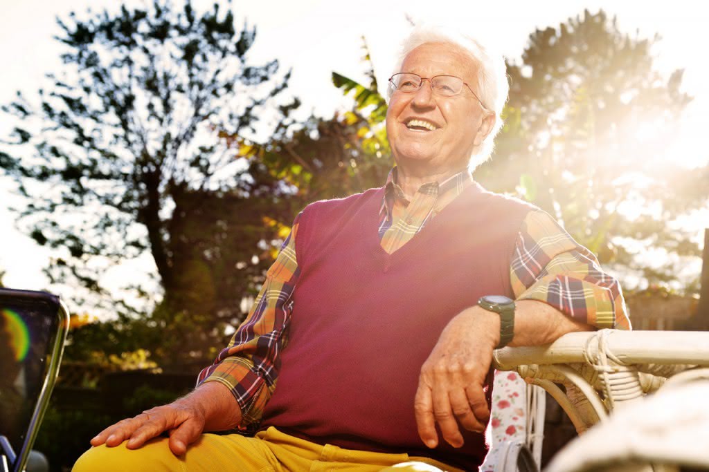 Mann sitzt im Sonnenschein im Garten