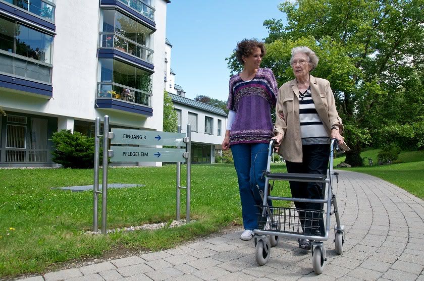 Seniorin und junge Frau vor Seniorenheim