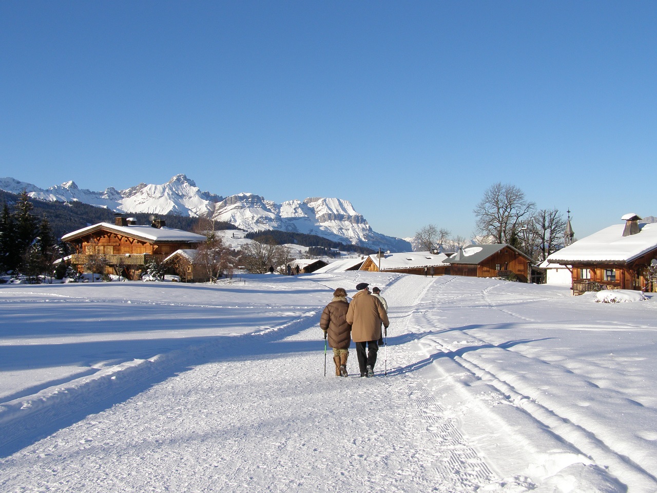 Senioren Paar geht auf einer verschneiten Straße vor Bergpanorama entlang