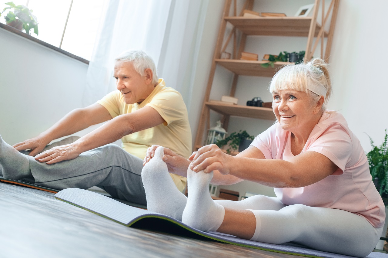 Älteres Paar macht Sport auf Yogamatten im Wohnzimmer