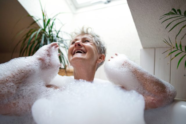 Seniorin sitzt auf Badewanne